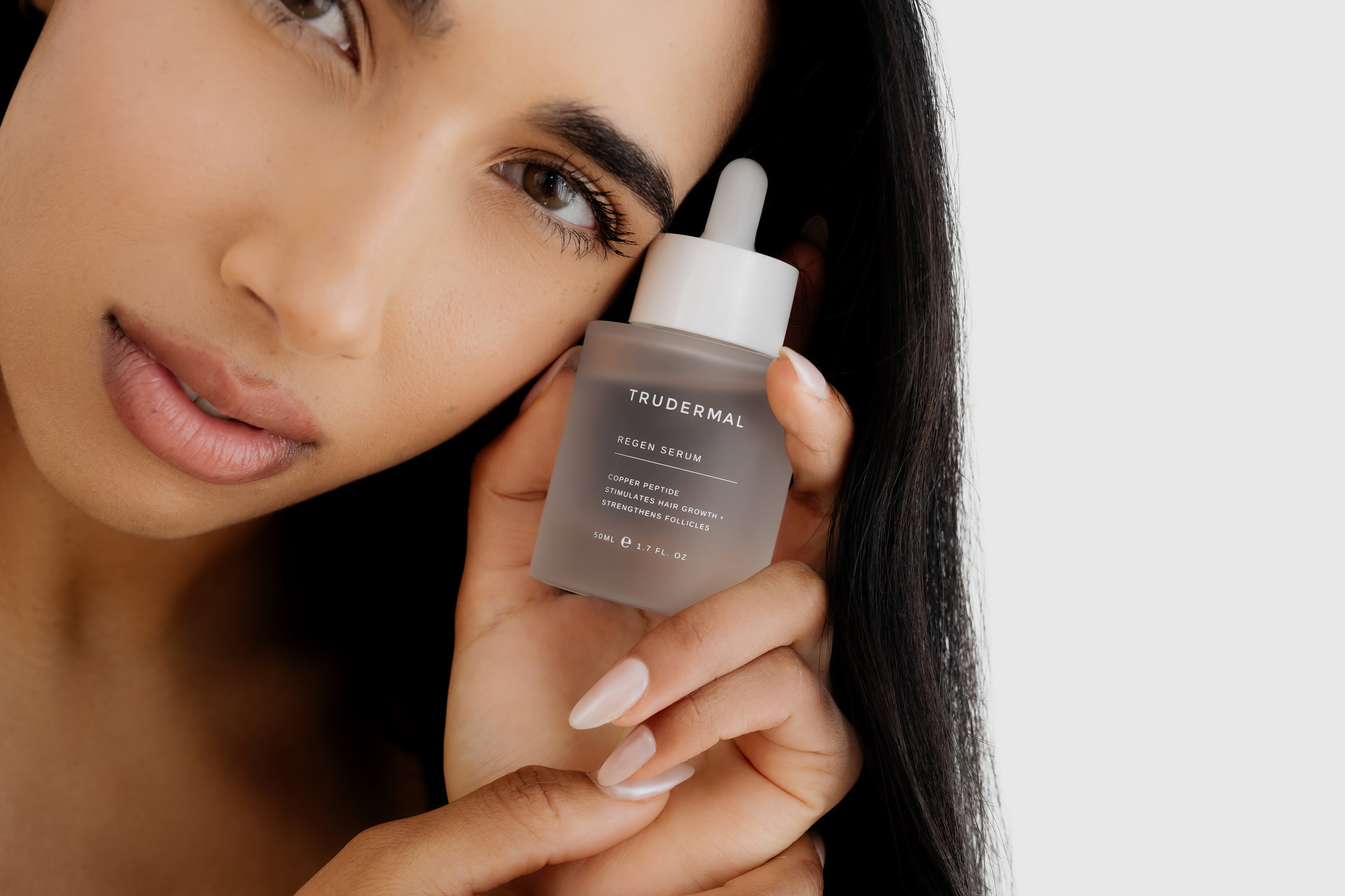 Woman holding Regen Hair Growth Serum formulated to support scalp health and promote stronger, fuller hair.