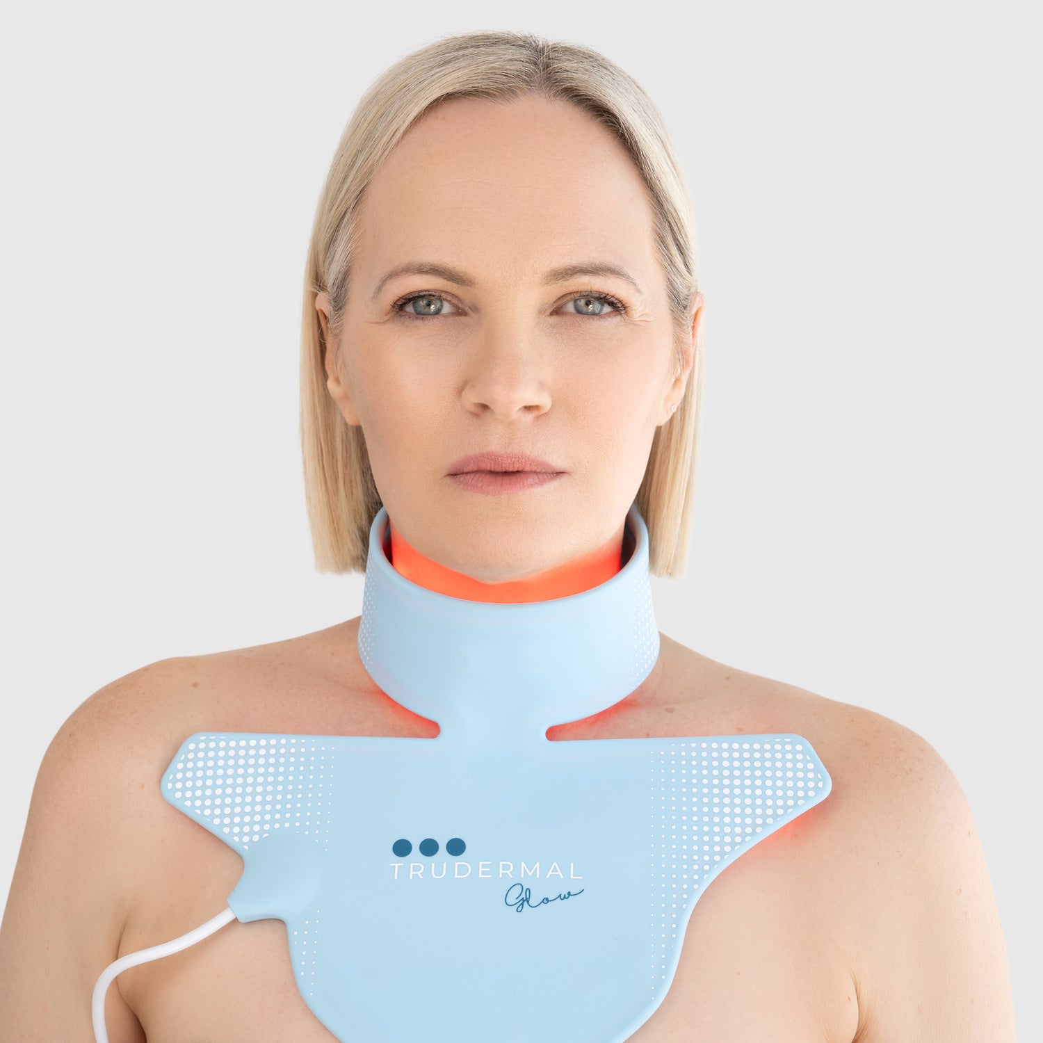 Woman wearing Trudermal LED neck and décolletage light therapy mask designed to boost collagen and improve skin firmness.