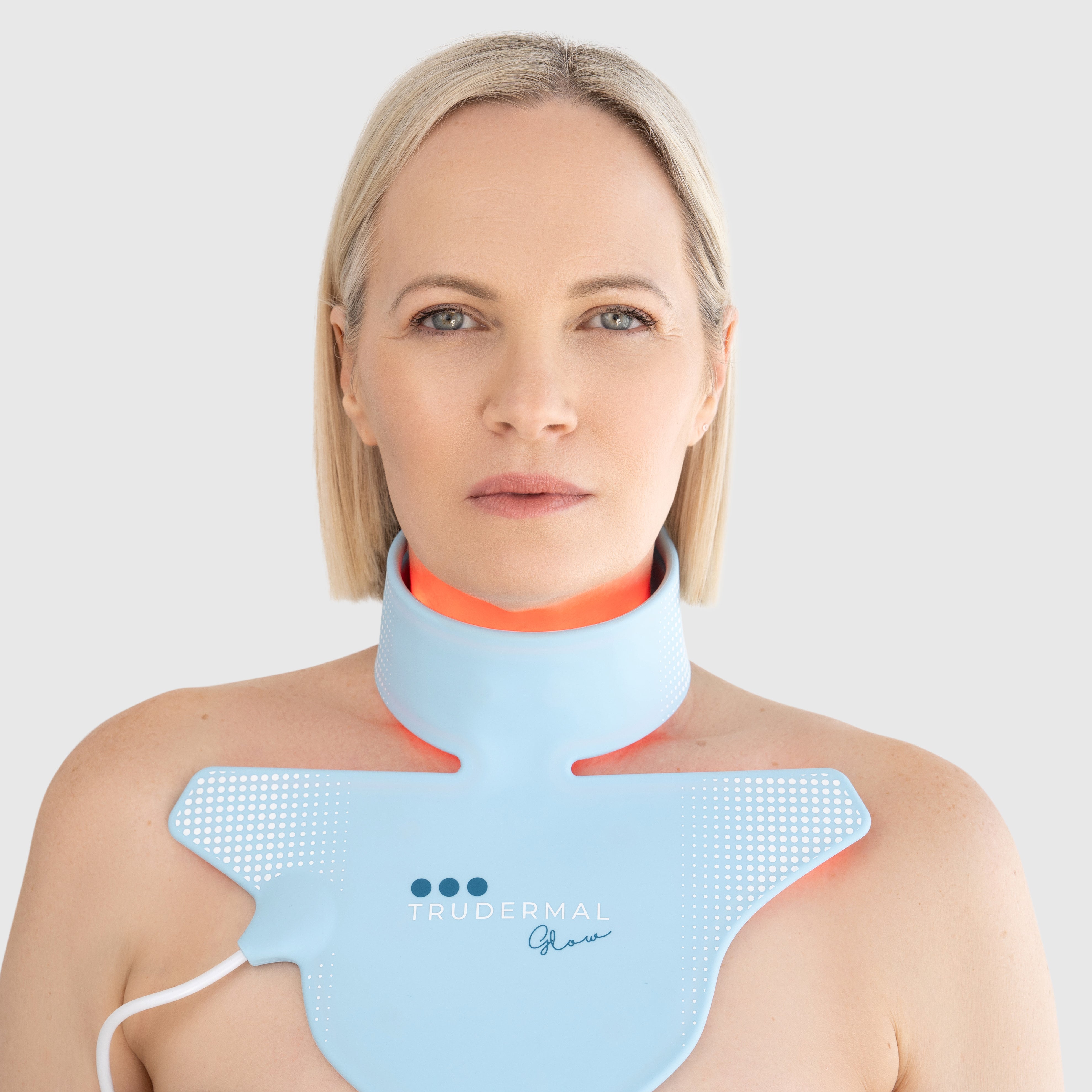 Woman wearing Trudermal LED neck and décolletage light therapy mask designed to boost collagen and improve skin firmness.