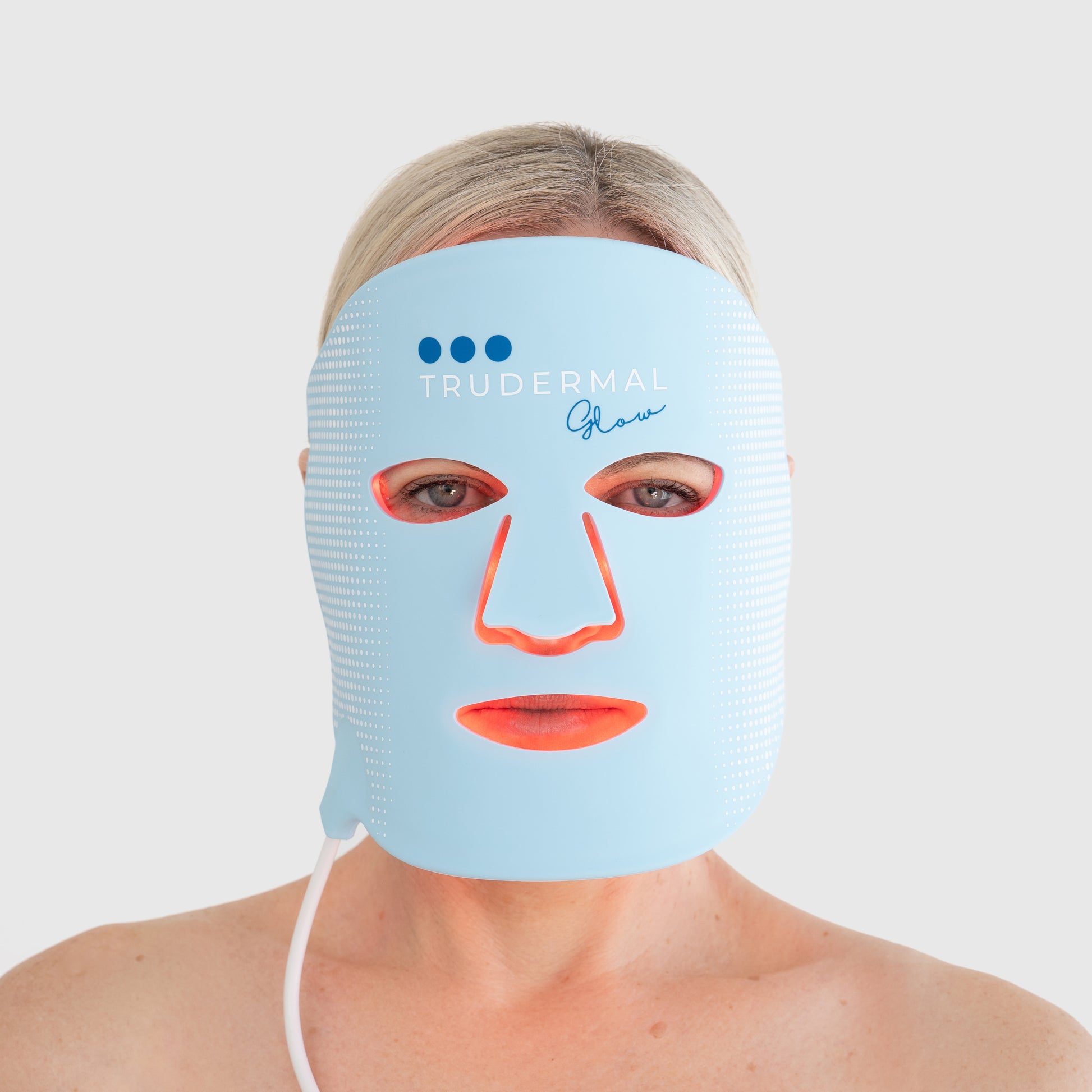 Woman wearing the Trudermal Glow LED light therapy mask designed to treat acne, boost collagen and improve skin tone.