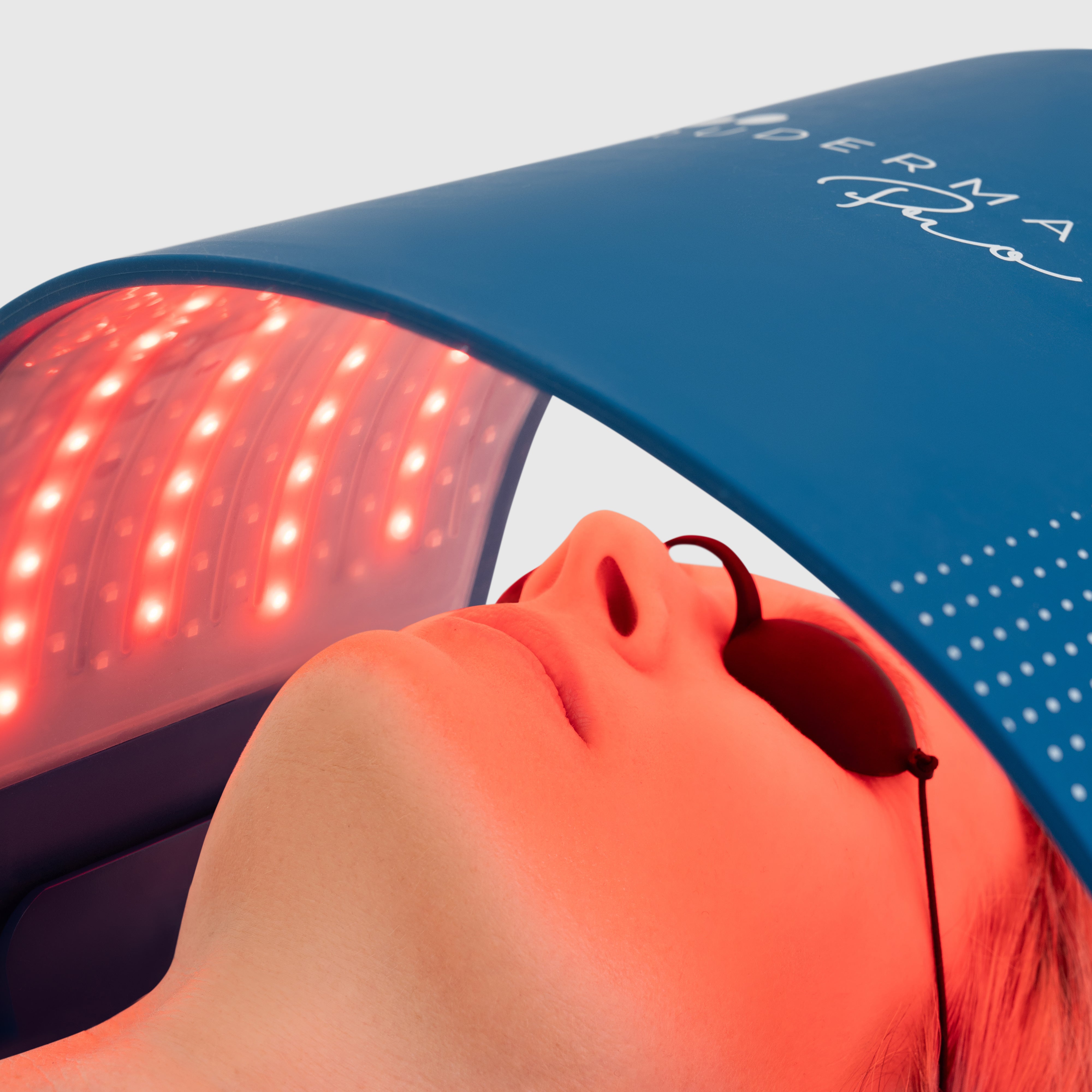 Woman receiving LED light therapy treatment under the Trudermal Pro device to boost collagen, improve skin tone and reduce acne.
